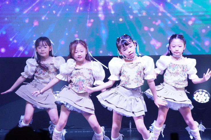 K-POPダンスショーケースイベント「Dance it UP」大阪開催のステージ写真。キッズダンサーたちが照明に包まれながら力強くパフォーマンスを披露している。
