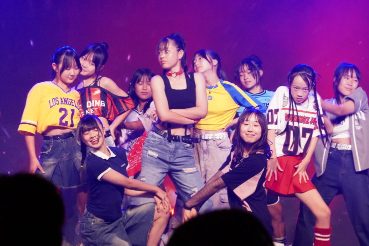 K-POPダンスショーケースイベント「Dance it UP」名古屋開催のステージ写真。カジュアルなストリートスタイルの衣装を着たチームが、力強く息の合ったパフォーマンスを披露している。